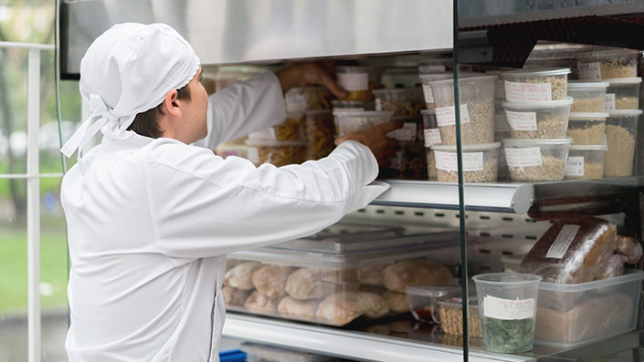 food worker storing food in refrigerator