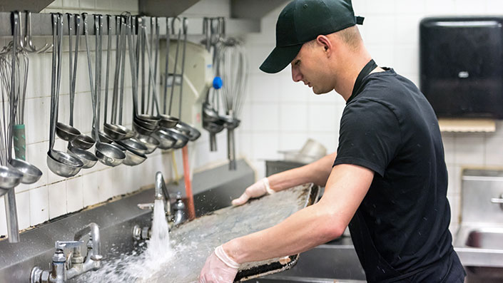 worker cleaning baking pan